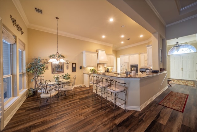 kitchen featuring a kitchen breakfast bar, kitchen peninsula, white cabinetry, and dark wood-type flooring