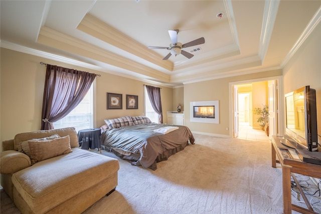 carpeted bedroom with ceiling fan, a raised ceiling, ornamental molding, and ensuite bath