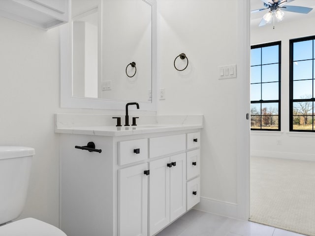 bathroom featuring ceiling fan, vanity, a healthy amount of sunlight, and toilet