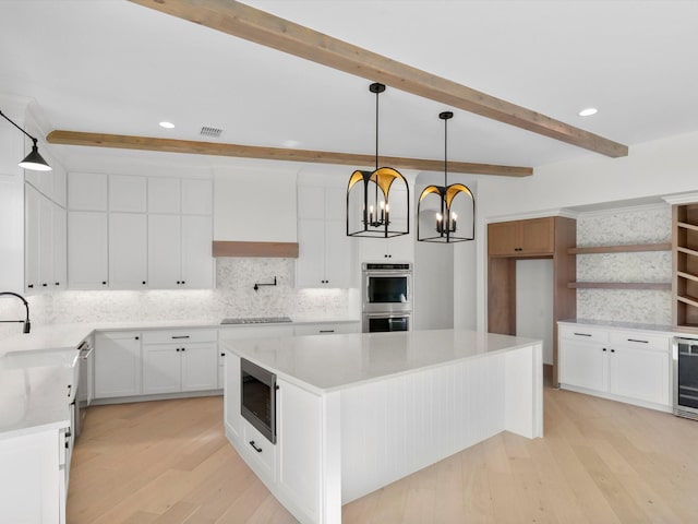 kitchen featuring white cabinets, light hardwood / wood-style flooring, beamed ceiling, and a kitchen island