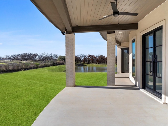 view of patio with a water view and ceiling fan