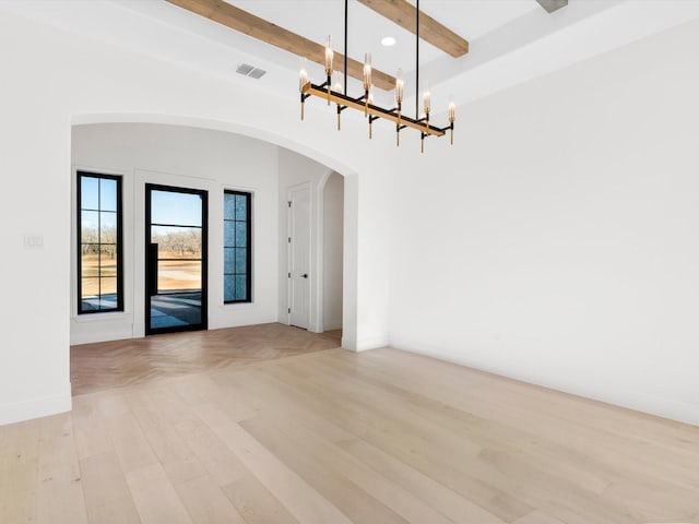 spare room with beamed ceiling, a notable chandelier, and light hardwood / wood-style floors