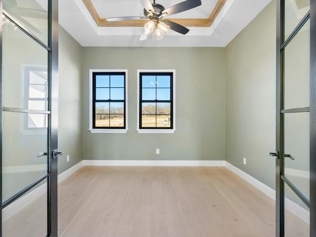 spare room with french doors, light wood-type flooring, a tray ceiling, and ceiling fan