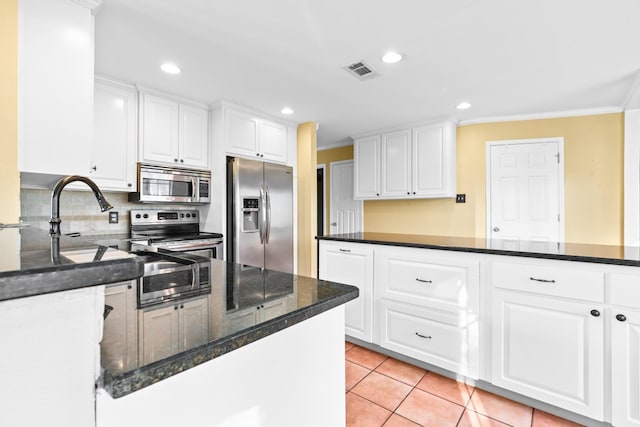 kitchen featuring decorative backsplash, white cabinetry, light tile patterned floors, and appliances with stainless steel finishes