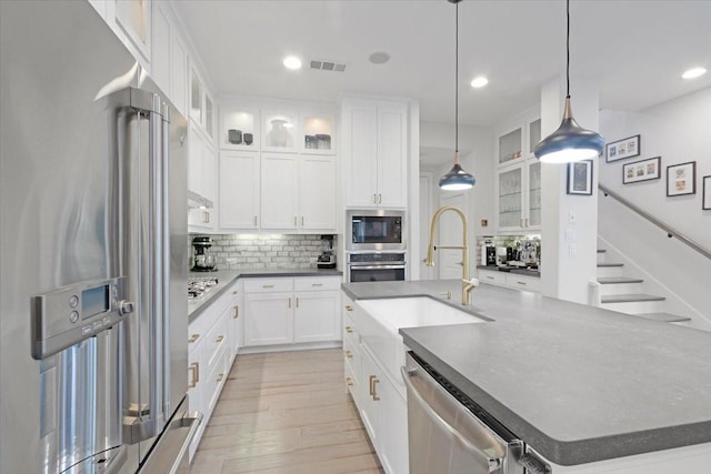 kitchen with decorative light fixtures, tasteful backsplash, an island with sink, stainless steel appliances, and white cabinets