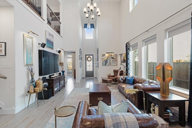 living room with a towering ceiling, an inviting chandelier, and light hardwood / wood-style floors