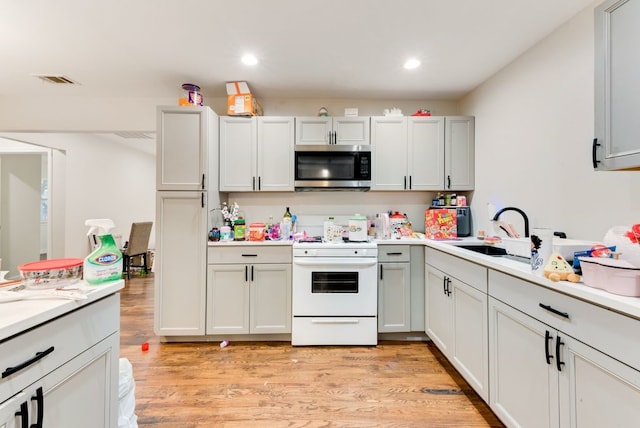 kitchen featuring electric range, sink, and light wood-type flooring