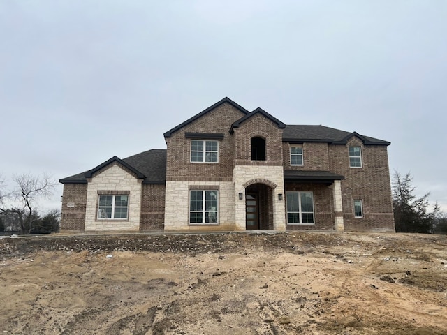 view of front of property with stone siding, brick siding, and roof with shingles