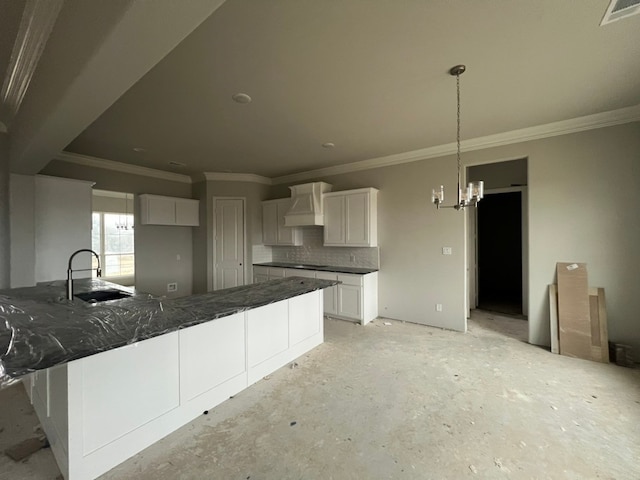 kitchen featuring tasteful backsplash, visible vents, white cabinets, wall chimney range hood, and a sink