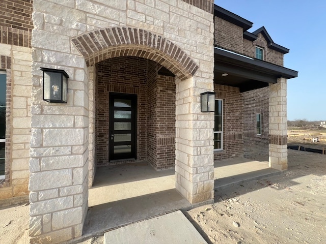 view of exterior entry with stone siding and brick siding