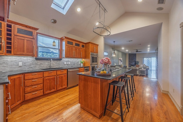 kitchen featuring a center island, a skylight, ceiling fan, tasteful backsplash, and stainless steel appliances