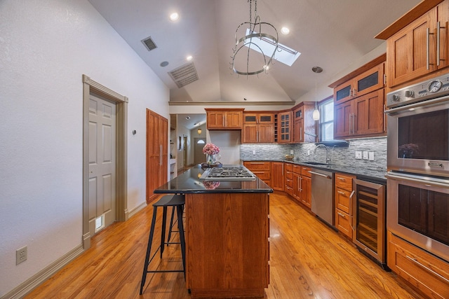 kitchen featuring pendant lighting, a center island, lofted ceiling with skylight, light hardwood / wood-style floors, and stainless steel appliances