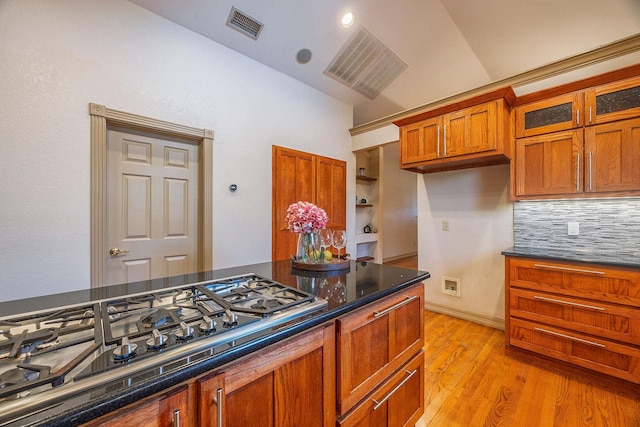 kitchen with decorative backsplash, light hardwood / wood-style flooring, vaulted ceiling, and stainless steel gas cooktop