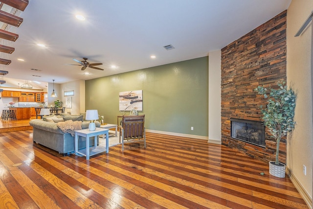 living room featuring a fireplace, ceiling fan, and dark wood-type flooring