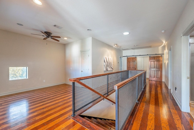 hallway featuring a barn door and dark hardwood / wood-style floors