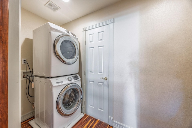 washroom with hardwood / wood-style flooring and stacked washer and dryer