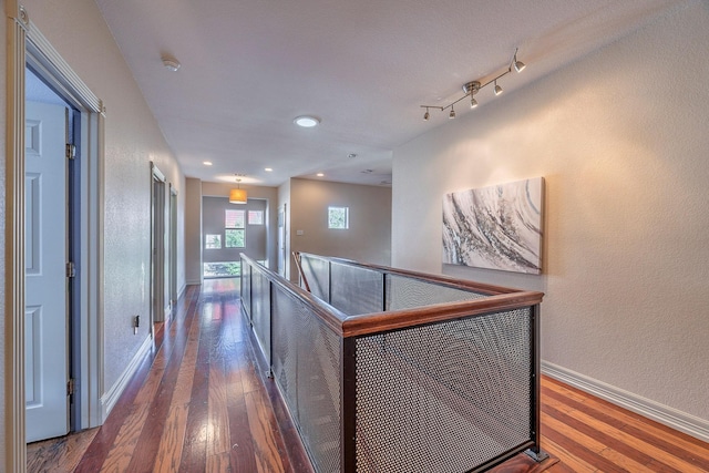 hallway with dark hardwood / wood-style flooring and rail lighting