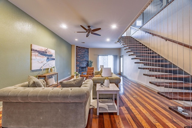 living room featuring ceiling fan, a fireplace, and dark wood-type flooring