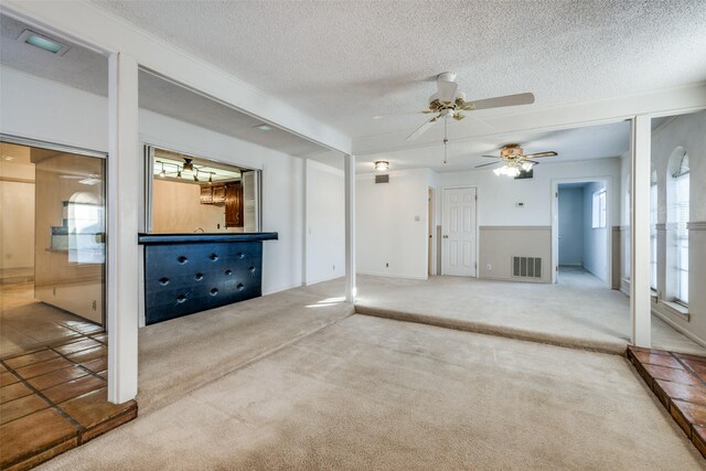 unfurnished living room with a textured ceiling, carpet floors, and a wealth of natural light