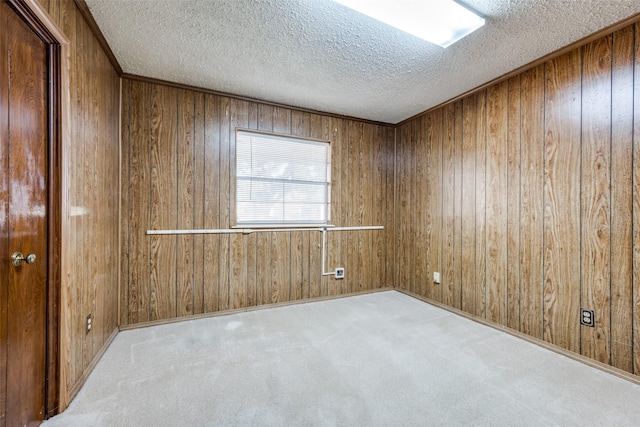 empty room featuring wooden walls, light carpet, and a textured ceiling