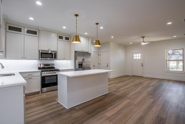 kitchen with stainless steel appliances, ceiling fan, sink, a center island, and dark hardwood / wood-style floors