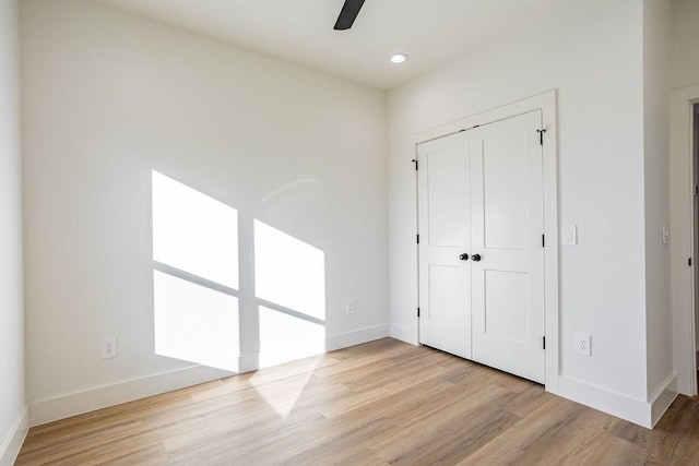 unfurnished bedroom featuring ceiling fan, a closet, and light wood-type flooring