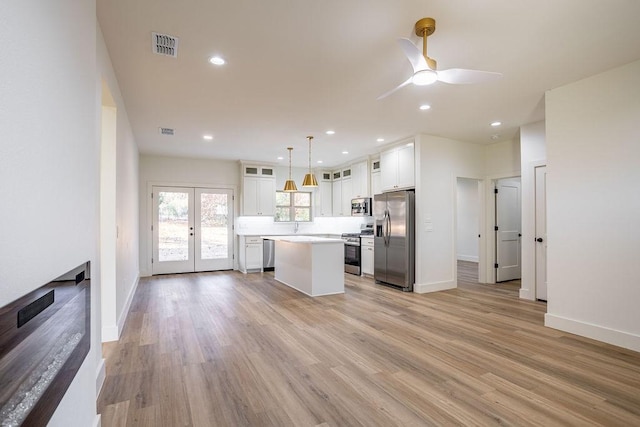 kitchen featuring pendant lighting, white cabinetry, stainless steel appliances, light hardwood / wood-style floors, and a kitchen island