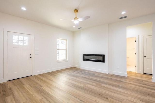 unfurnished living room featuring heating unit, light hardwood / wood-style floors, and ceiling fan