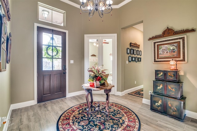 foyer with ornamental molding, an inviting chandelier, and light hardwood / wood-style flooring