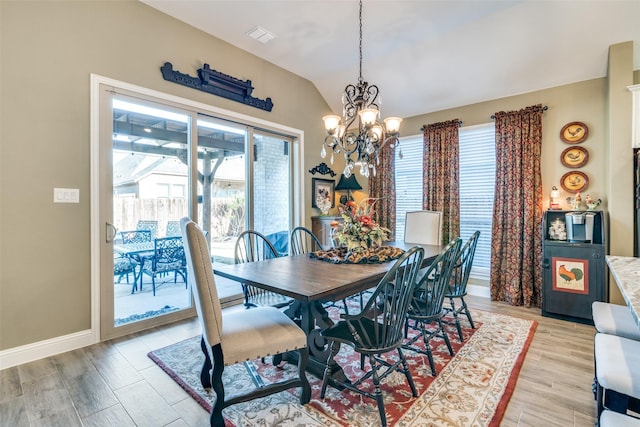dining room featuring an inviting chandelier, a healthy amount of sunlight, lofted ceiling, and light wood-type flooring