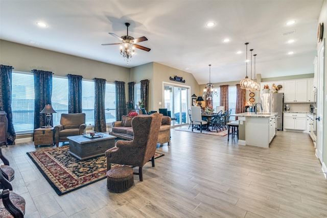 living area featuring visible vents, vaulted ceiling, light wood-type flooring, ceiling fan with notable chandelier, and recessed lighting