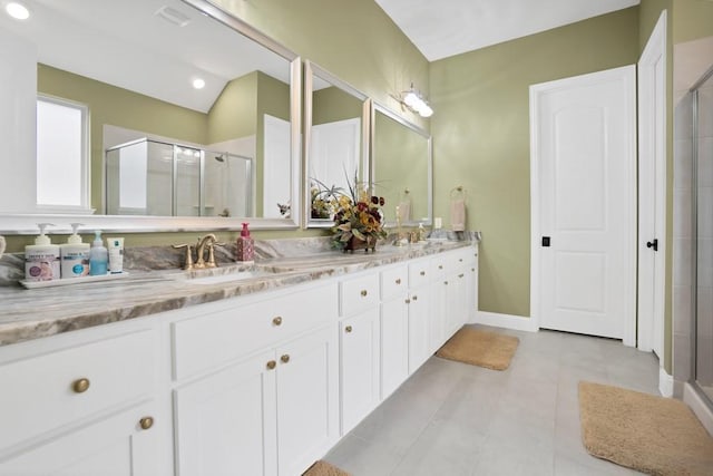 bathroom with double vanity, baseboards, a shower stall, and a sink