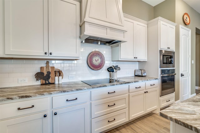kitchen featuring light stone counters, white cabinets, custom range hood, light wood finished floors, and stainless steel appliances