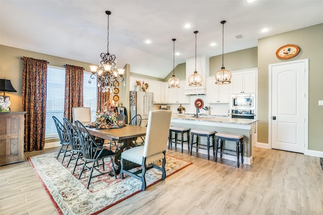 dining room with light wood finished floors, visible vents, a chandelier, baseboards, and vaulted ceiling