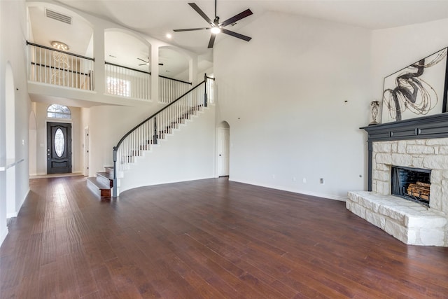 unfurnished living room featuring a fireplace, high vaulted ceiling, ceiling fan, and dark wood-type flooring