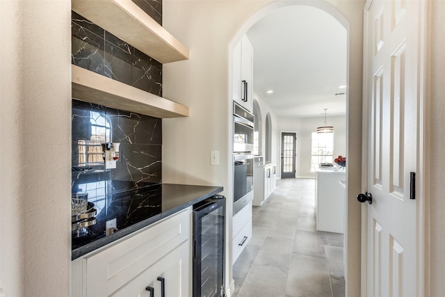 bar with white cabinets, light tile patterned floors, tasteful backsplash, decorative light fixtures, and beverage cooler