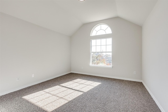 carpeted empty room with lofted ceiling