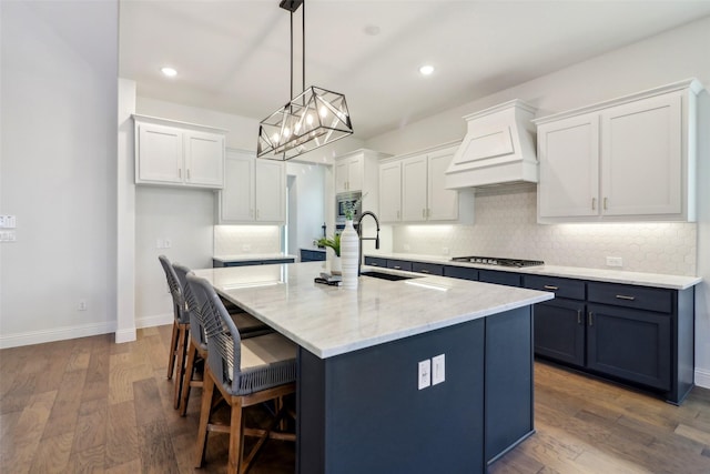 kitchen featuring sink, white cabinets, custom range hood, and stainless steel appliances