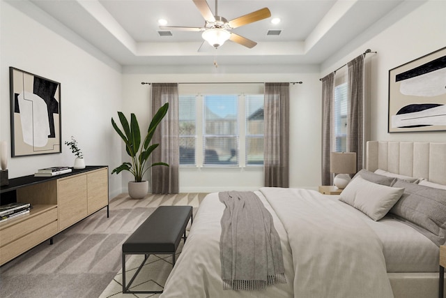 bedroom featuring light carpet, multiple windows, ceiling fan, and a raised ceiling