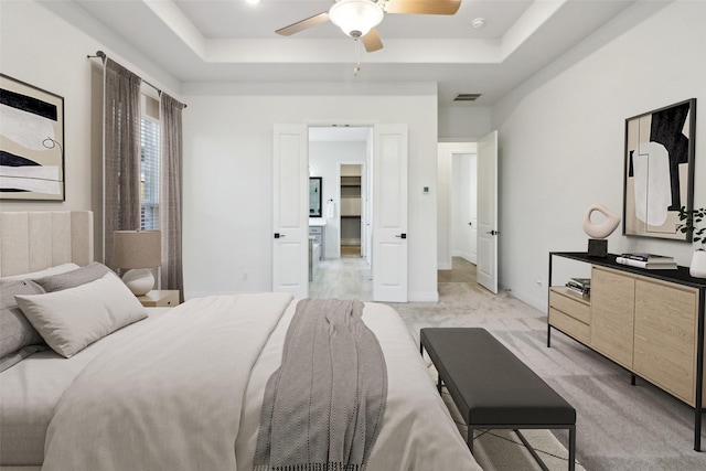 bedroom with multiple windows, ceiling fan, light carpet, and a tray ceiling