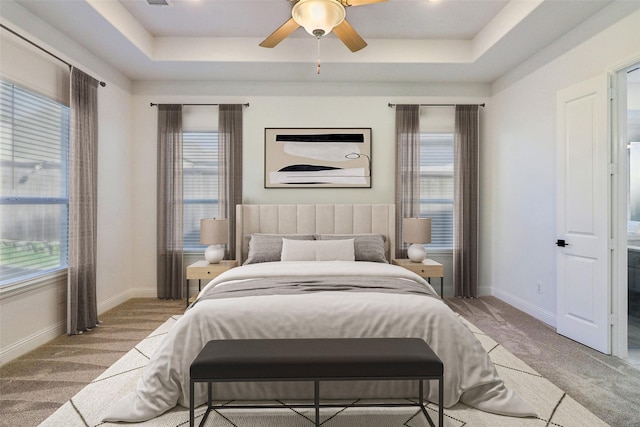 bedroom featuring light carpet, ceiling fan, and a raised ceiling