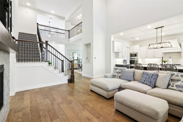 living room featuring a stone fireplace, a high ceiling, and light hardwood / wood-style flooring