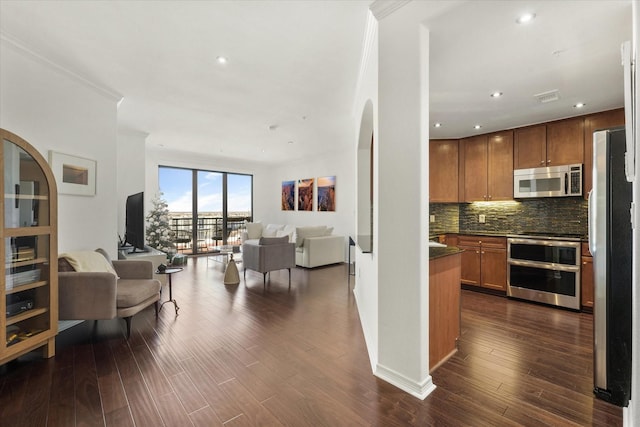 kitchen featuring stainless steel appliances, ornamental molding, dark wood-type flooring, and decorative backsplash