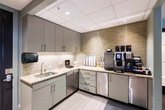 kitchen featuring sink, light stone counters, fridge, dishwasher, and decorative backsplash