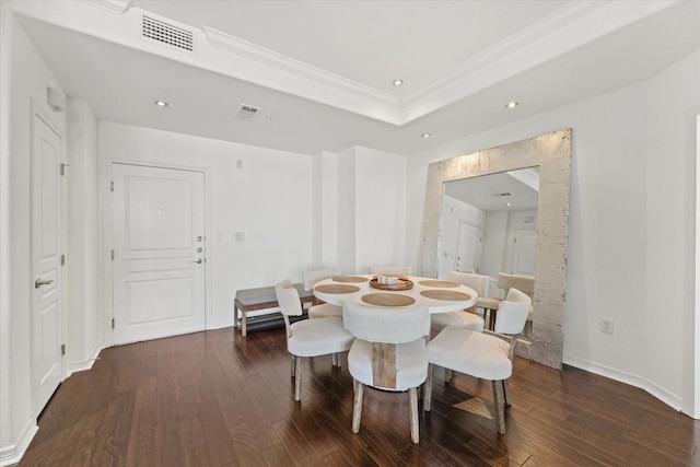 dining space with ornamental molding, dark wood-type flooring, and a tray ceiling