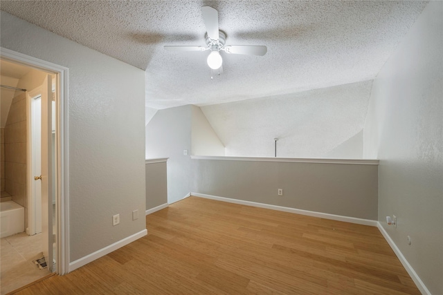 bonus room with a textured ceiling, ceiling fan, vaulted ceiling, and light wood-type flooring