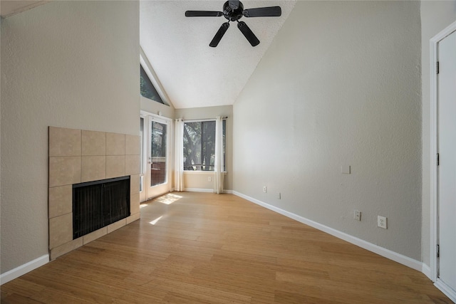 unfurnished living room featuring a textured ceiling, ceiling fan, a tile fireplace, light hardwood / wood-style floors, and lofted ceiling