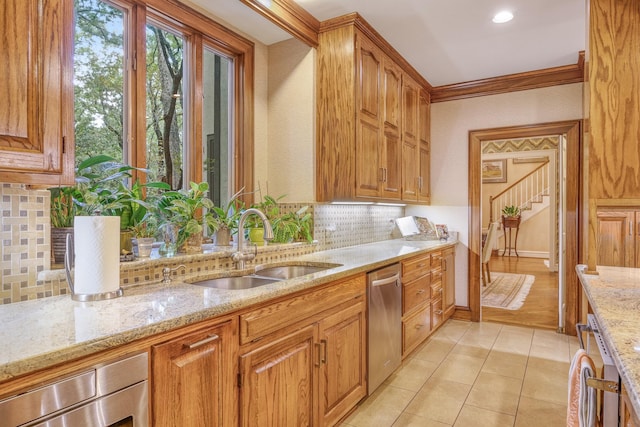 kitchen featuring sink, dishwasher, light stone counters, light hardwood / wood-style flooring, and decorative backsplash