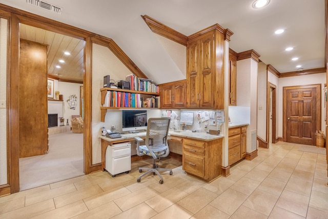 carpeted home office with built in desk, ornamental molding, and vaulted ceiling