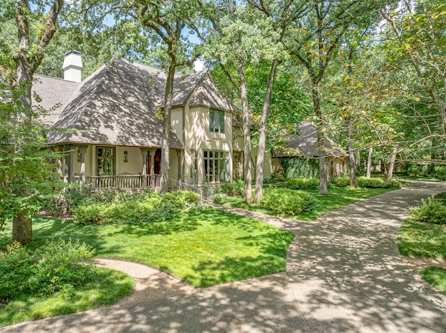 tudor-style house featuring covered porch and a front yard